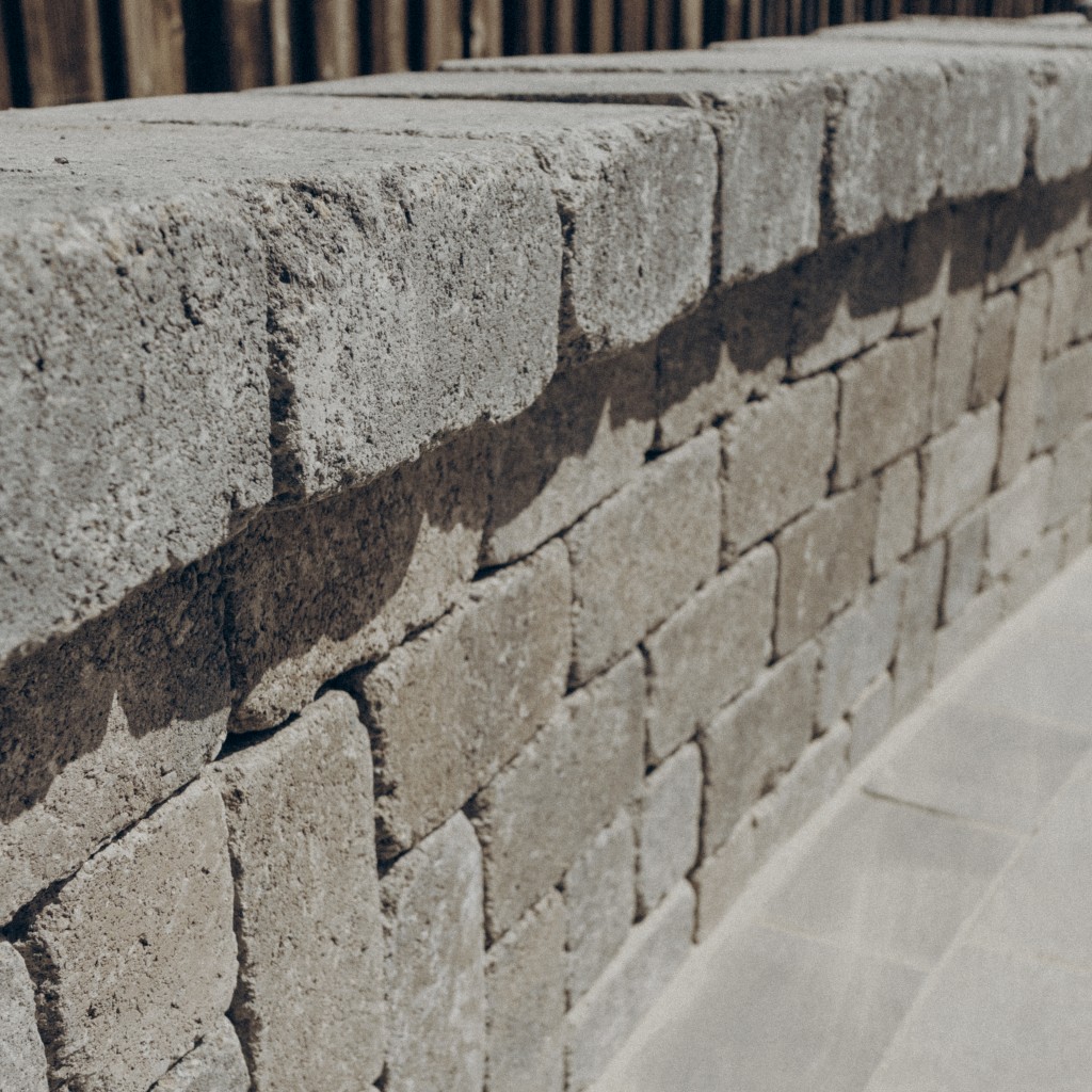 Photo of a light gray retaining wall made of stacked pavers